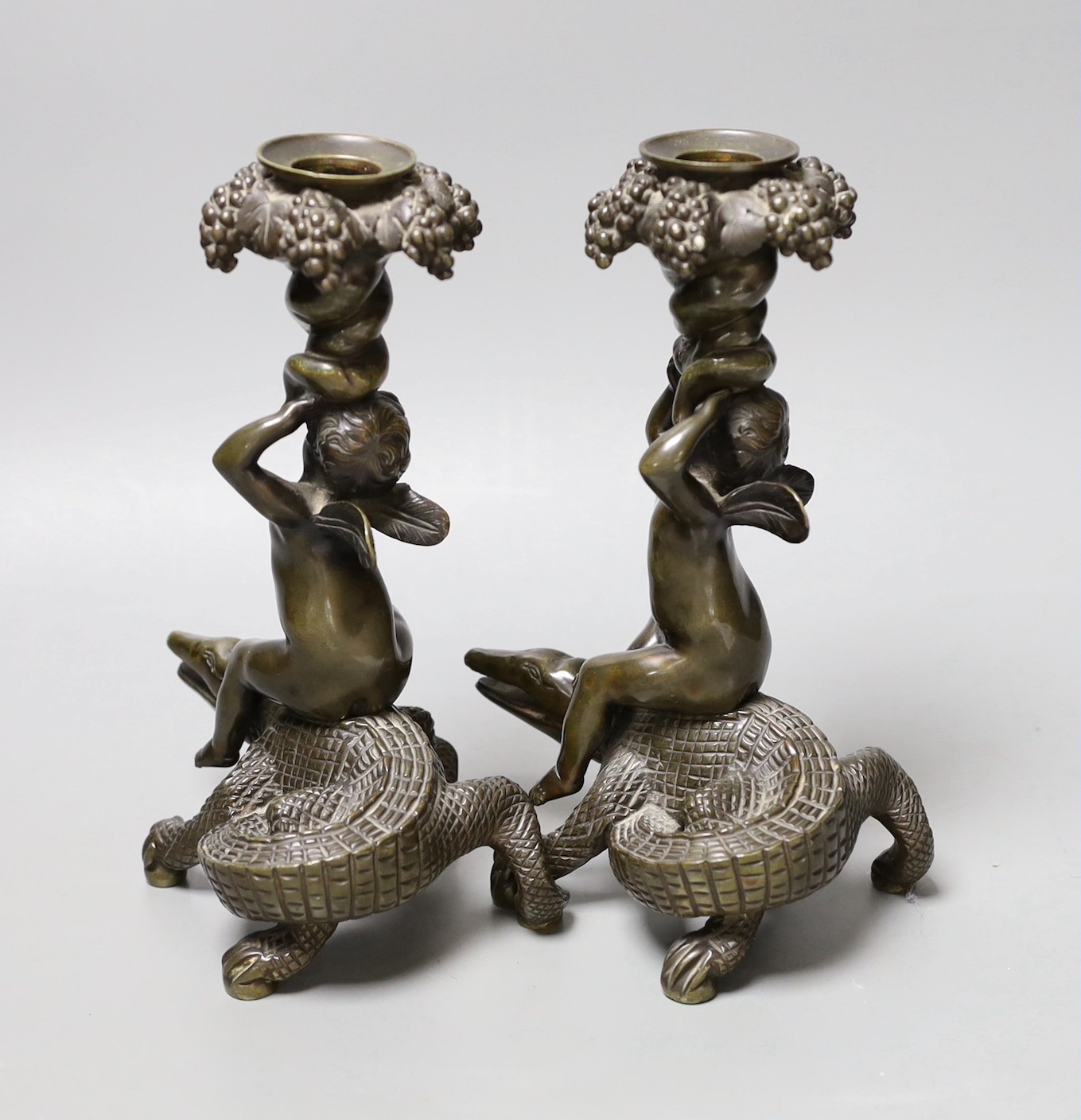 A pair of late 19th century bronze candlesticks modelled as cherubs riding crocodiles, 21.5cm